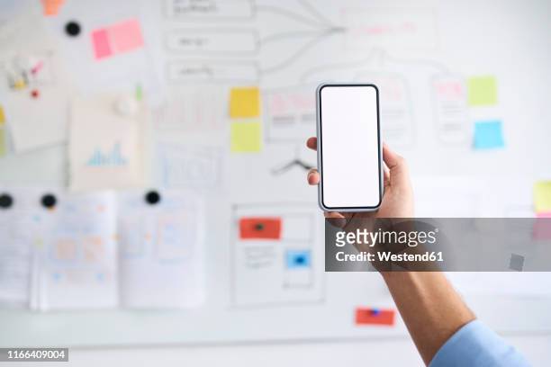 male hand holding aloft a smartphone in front of a whiteboard - holding up line stock pictures, royalty-free photos & images
