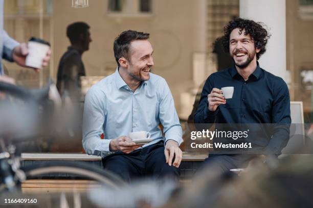 friends sitting in front of coffee shop, talking, drinking coffee - two executive man coffee shop stockfoto's en -beelden