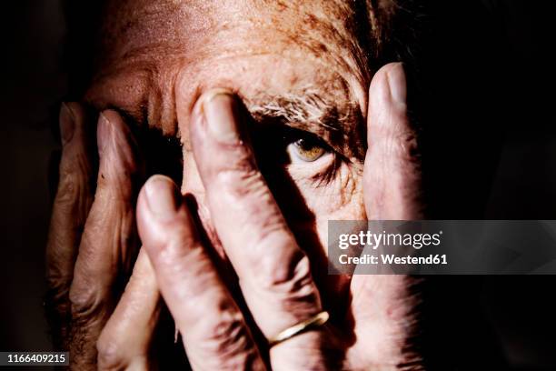 senior man covering face with hands, close-up - alzheimers stock-fotos und bilder