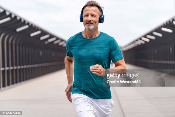 sporty man wearing headphones and jogging - mature men sports stock pictures, royalty-free photos & images