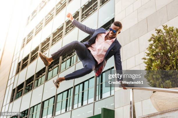 young businessman jumping mid-air - black suit sunglasses stock pictures, royalty-free photos & images