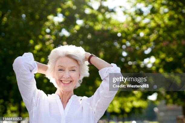 portrait of happy mature woman in nature - 髪に手をやる　女性 ストックフォトと画像