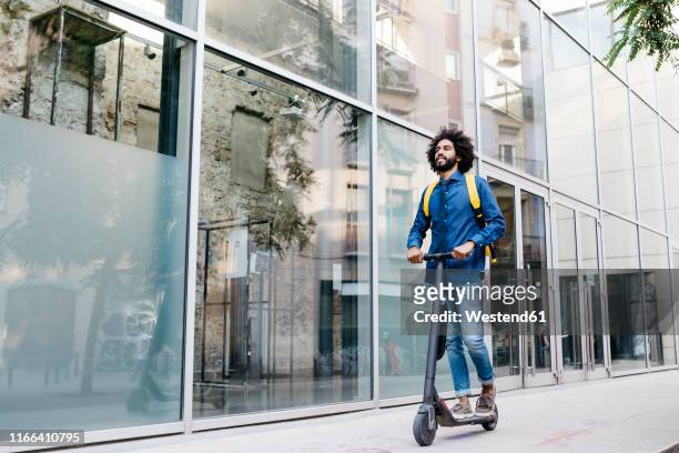 man with backpack riding fast with his e-scooter on pavement - man backpack stock pictures, royalty-free photos & images