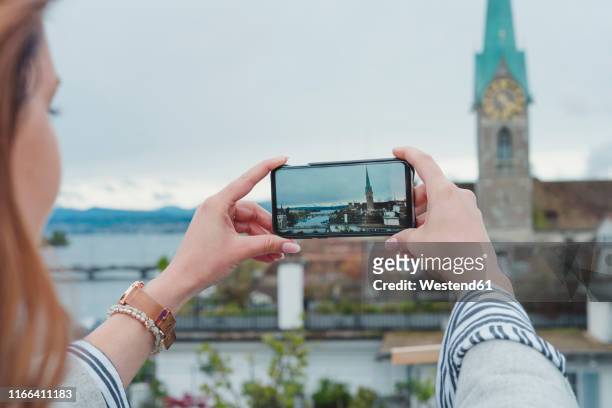 young woman taking smartphone picture in the city, zurich, switzerland - online church stock pictures, royalty-free photos & images
