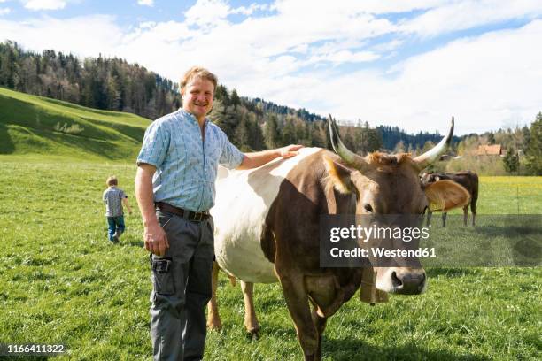 portrait of confident farmer with cow on pasture - swiss culture photos et images de collection