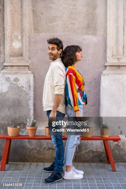 couple standing back to back on pavement - back to back stockfoto's en -beelden