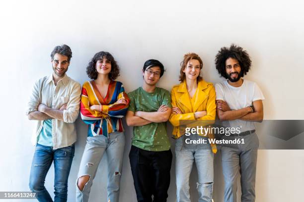 portrait of confident group of friends standing at a wall - five people stock pictures, royalty-free photos & images