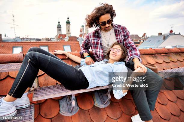 young couple relaxing on rooftop - munich stock-fotos und bilder