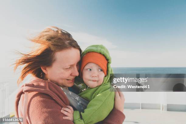 mother carrying baby boy in a sling on a ferry - ferry passenger stock pictures, royalty-free photos & images