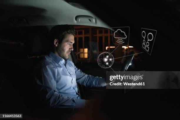 businessman using device in car at night surrounded by internet symbols - augmented reality car stockfoto's en -beelden