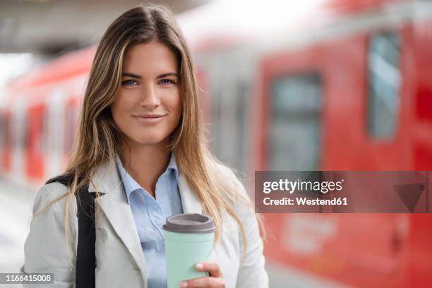 young businesswoman with coffee to go cup, standing on station - münchen business stock pictures, royalty-free photos & images