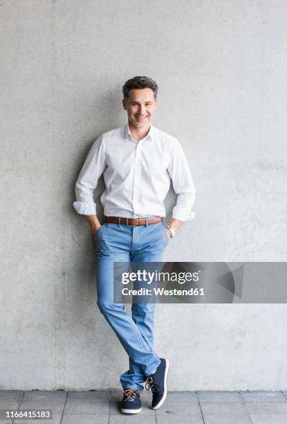 businessman wearing white shirt, grey wall in the background - front on portrait older full body foto e immagini stock