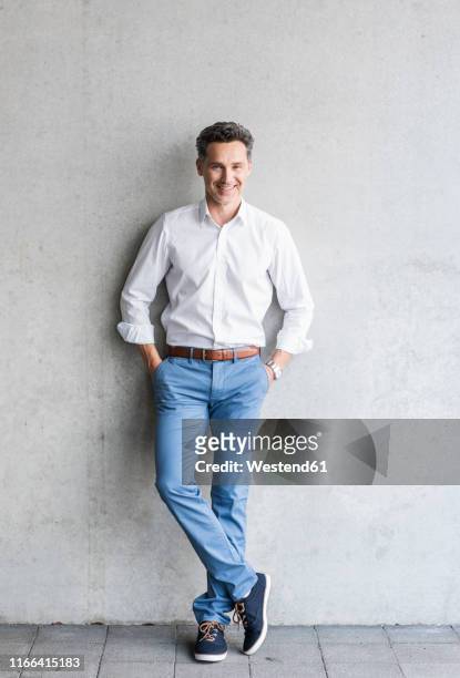 businessman wearing white shirt, grey wall in the background - leaning 個照片及圖片檔