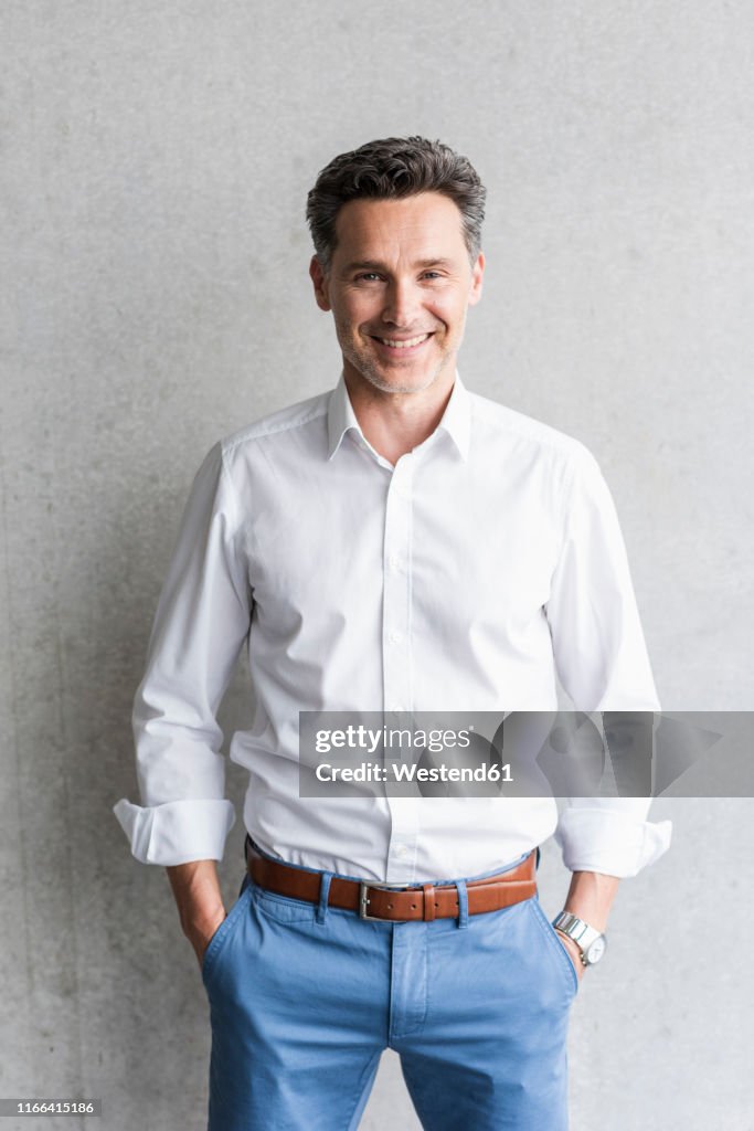 Businessman wearing white shirt, grey wall in the background