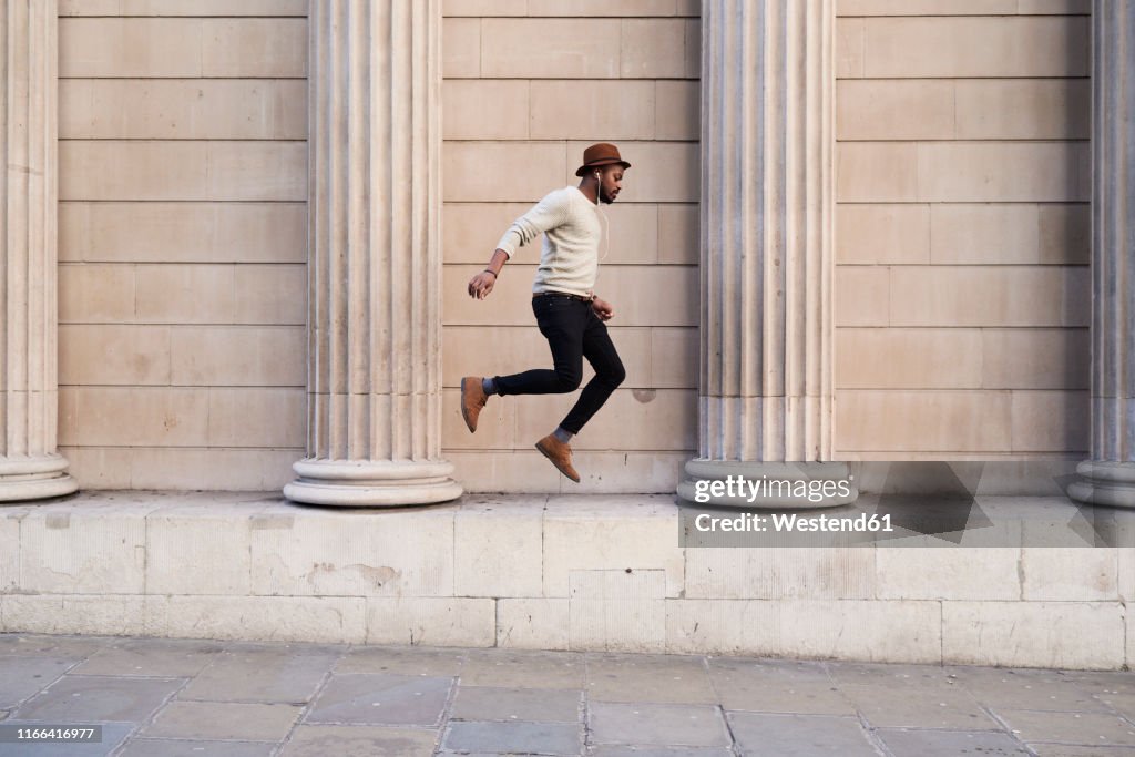 Mid adult man listening music and jumping