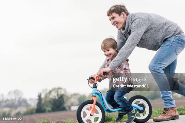 father teaching his son how to ride a bicycle, outdoors - riding bildbanksfoton och bilder