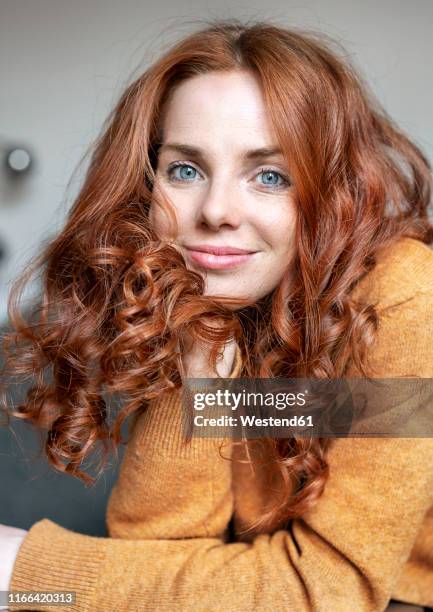 portrait of smiling redheaded woman with blue eyes - hand in den haaren stock-fotos und bilder