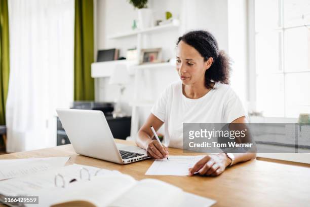 a single mom sitting at kitchen table working from home - frau aktenordner stock-fotos und bilder