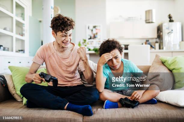 boy beating his younger brother at computer games - bad brother stock pictures, royalty-free photos & images