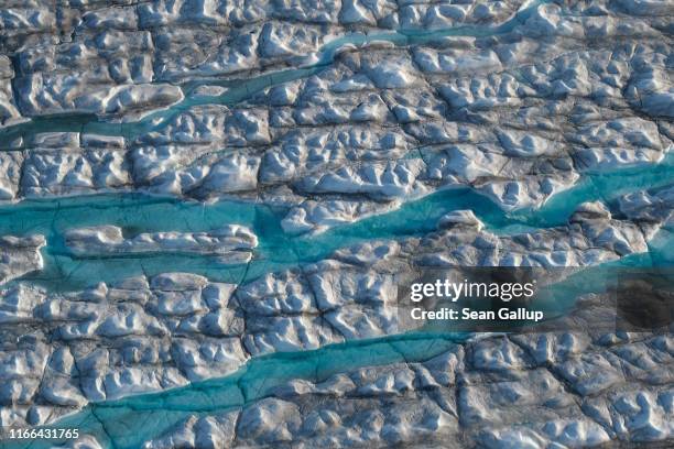 In this view from an airplane rivers of meltwater carve into the Greenland ice sheet near Sermeq Avangnardleq glacier on August 04, 2019 near...