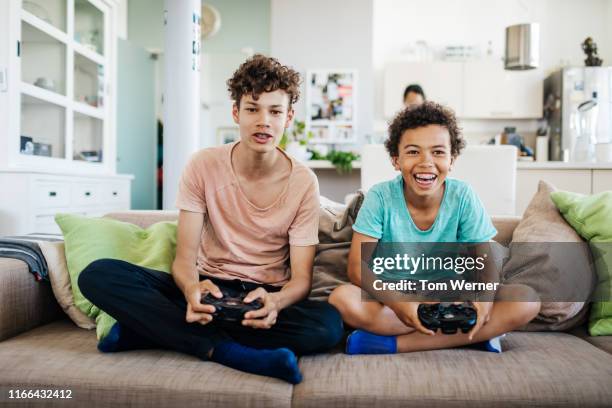 two brothers sitting on couch playing computer games - two young boys foto e immagini stock