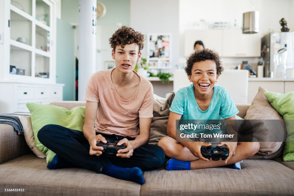 Two Brothers Sitting On Couch Playing Computer Games