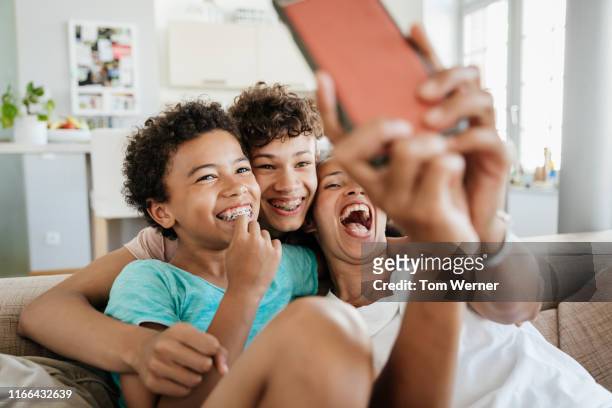 single mom having fun with her sons taking selfies - azul turquesa fotografías e imágenes de stock