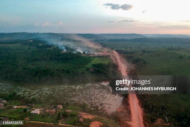 In this aerial view the red dust of the BR230 highway, known as "Transamazonica", mixes with fires at sunset in the agriculture town of Ruropolis,...