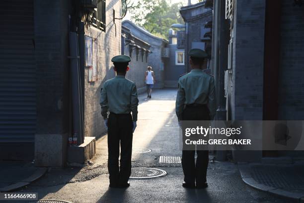 Chinese paramilitary police guard an alley in a street next to Tiananmen Square ahead of an overnight rehearsal of a military parade to mark...