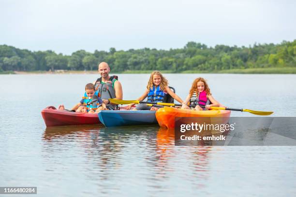 family of four in kayaks on lake - family red canoe stock pictures, royalty-free photos & images