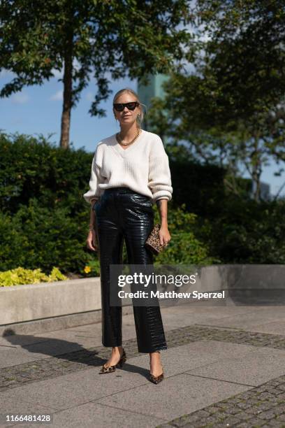 Guest is seen on the street during Copenhagen Fashion Week SS20 wearing white sweater, black leather pants and leopard print shoes and bag on August...