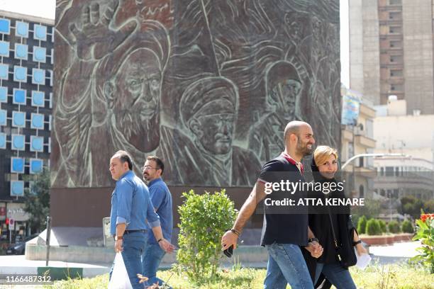 Pedestrians walk in front of a mural depicting former and current religious leaders at Enghelab Square in the Iranian capital Tehran. - Iran said...