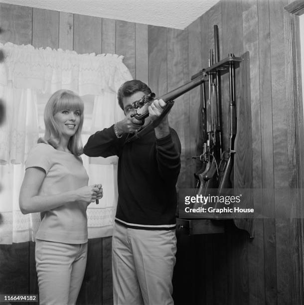 American singer and actor Fabian Forte at home with his wife Kathleen Regan and his rifle collection, circa 1968.
