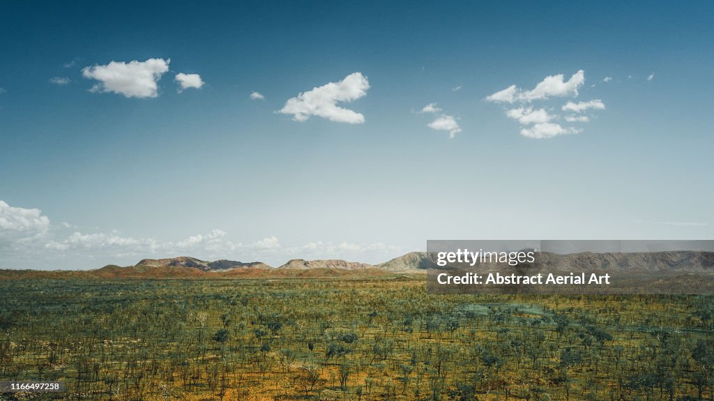 Aerial shot looking over remote bushland with a mountainous backdrop, Western Australia