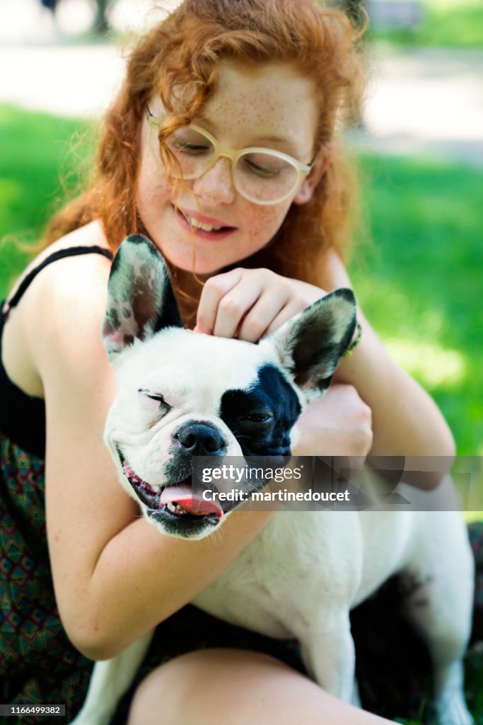 Teenage redhead girl in a park with a dog