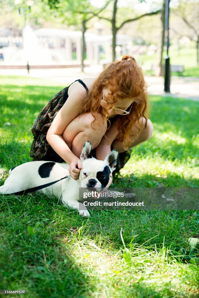 Teenage redhead girl in a park with a dog