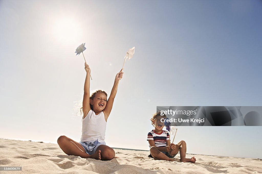 Children (4-5) playing with pinwheels on beach