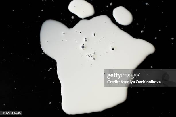 spilled milk puddle isolated on black background and texture with clipping path, top view - knoeien stockfoto's en -beelden