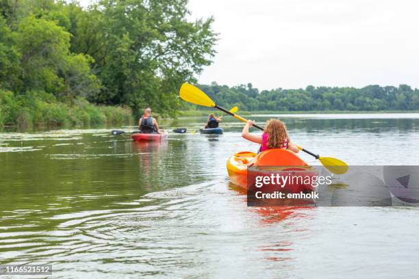 family kayaking on lake on summer evening - family red canoe stock pictures, royalty-free photos & images
