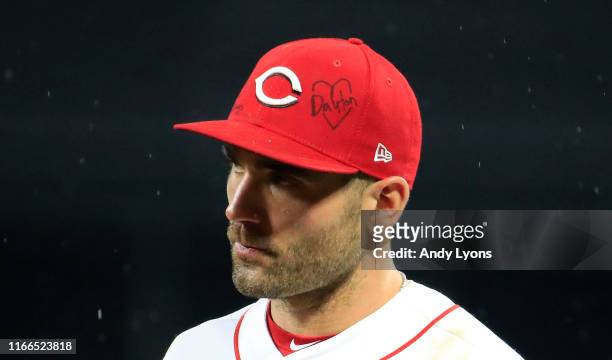 Joey Votto of the Cincinnati Reds wears a hat with a message in memory of victims of Sunday's mass shooting in Dayton, Ohio during the game against...