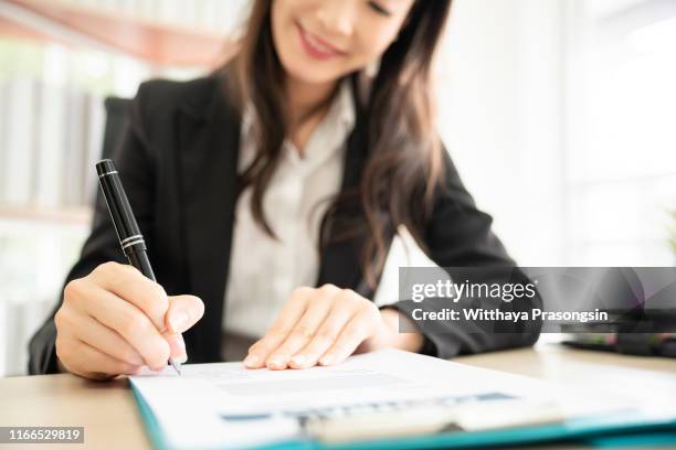 hand of businesswoman writing on paper in office - bank manager photos et images de collection