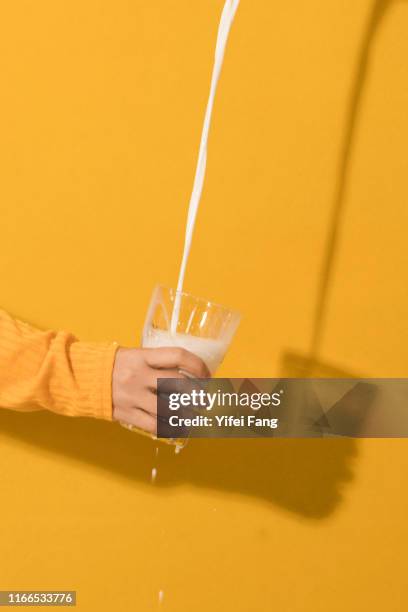 milk pouring into galss in front of color background - hand pouring stock pictures, royalty-free photos & images