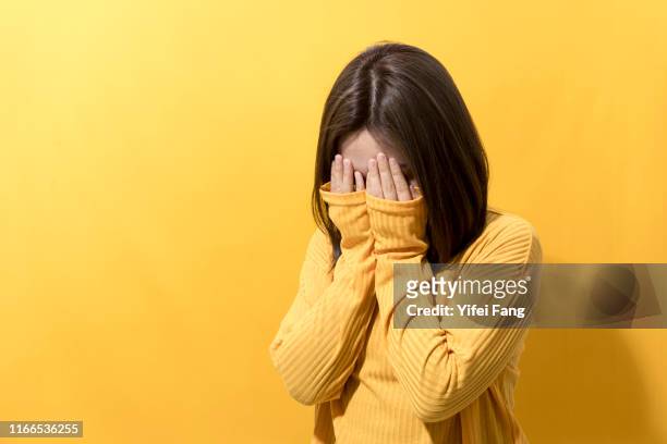 woman covering face in front of color background - shy stock pictures, royalty-free photos & images