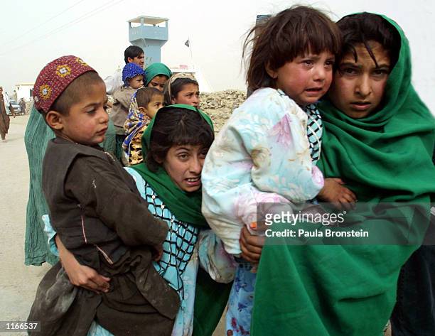 Afghans refugees walk across the border into Pakistan October 11, 2001 as they leave Afghanistan at the Chaman crossing point on the 4th day of...