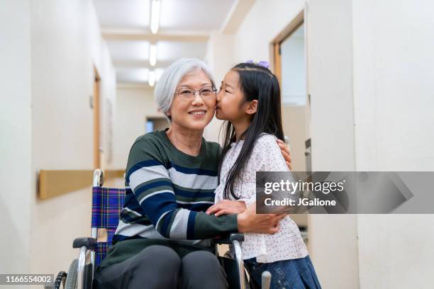 portrait of a grandmother in a wheelchair and her granddaughter at the hospital - hospital visit stock pictures, royalty-free photos & images