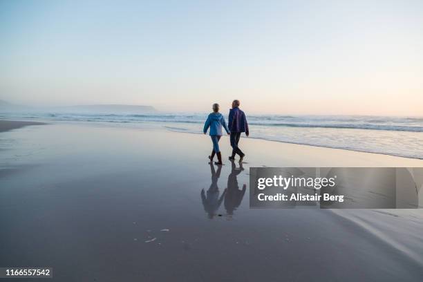 couple walking through shallow lagoon at sunset holding hands - enjoy nature fotografías e imágenes de stock