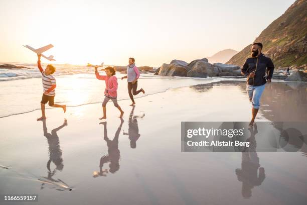 mixed race family running along beach with toy planes - action force stock pictures, royalty-free photos & images