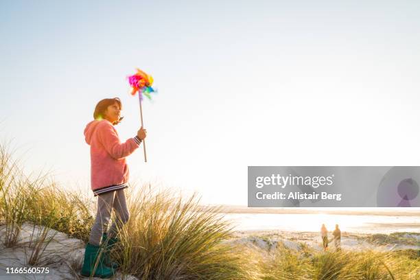 mixed race girl playing with pin wheel toy at the beach - the whirligig stockfoto's en -beelden