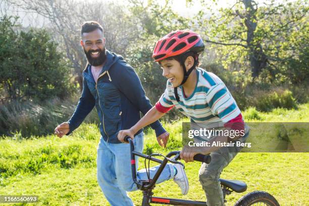 boy riding bike with his dad in the countryside - bicycle safety light stockfoto's en -beelden