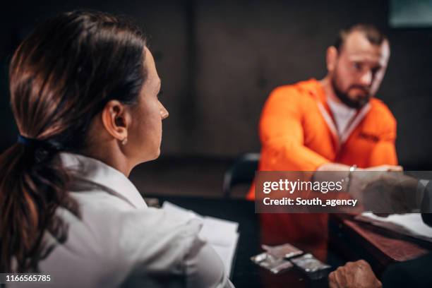 man prisoner shaking hand with lawyer in interrogation room - prison jumpsuit stock pictures, royalty-free photos & images